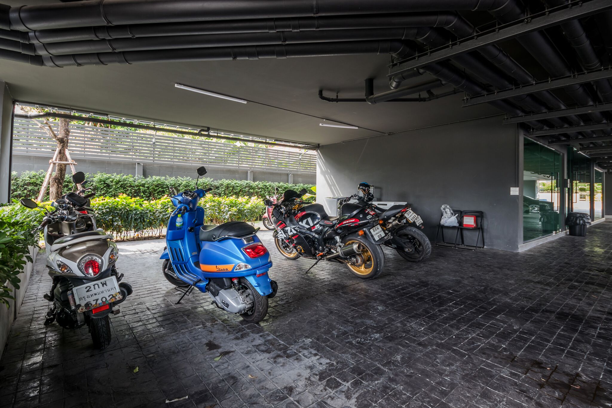 A covered parking area with scooters and motorcycles parked.
