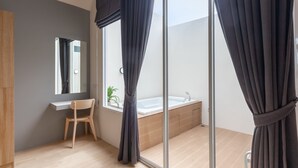 Une salle de bain moderne avec un meuble-lavabo en bois, un grand miroir, une baignoire et une fenêtre avec des rideaux.