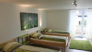 Un dormitorio con cuatro camas individuales, un escritorio y una alfombra verde.