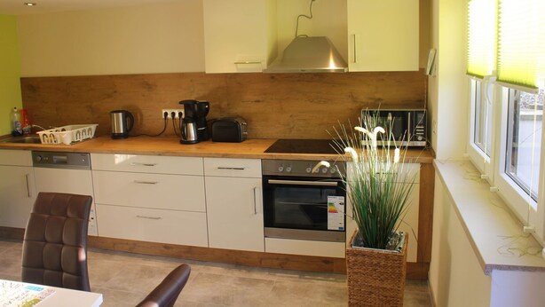 Una cocina moderna con armarios de madera, horno empotrado, cafetera y tostadora.