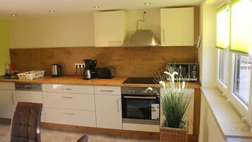 A modern kitchen with wooden cabinets, a built-in oven, a coffee maker, and a toaster.