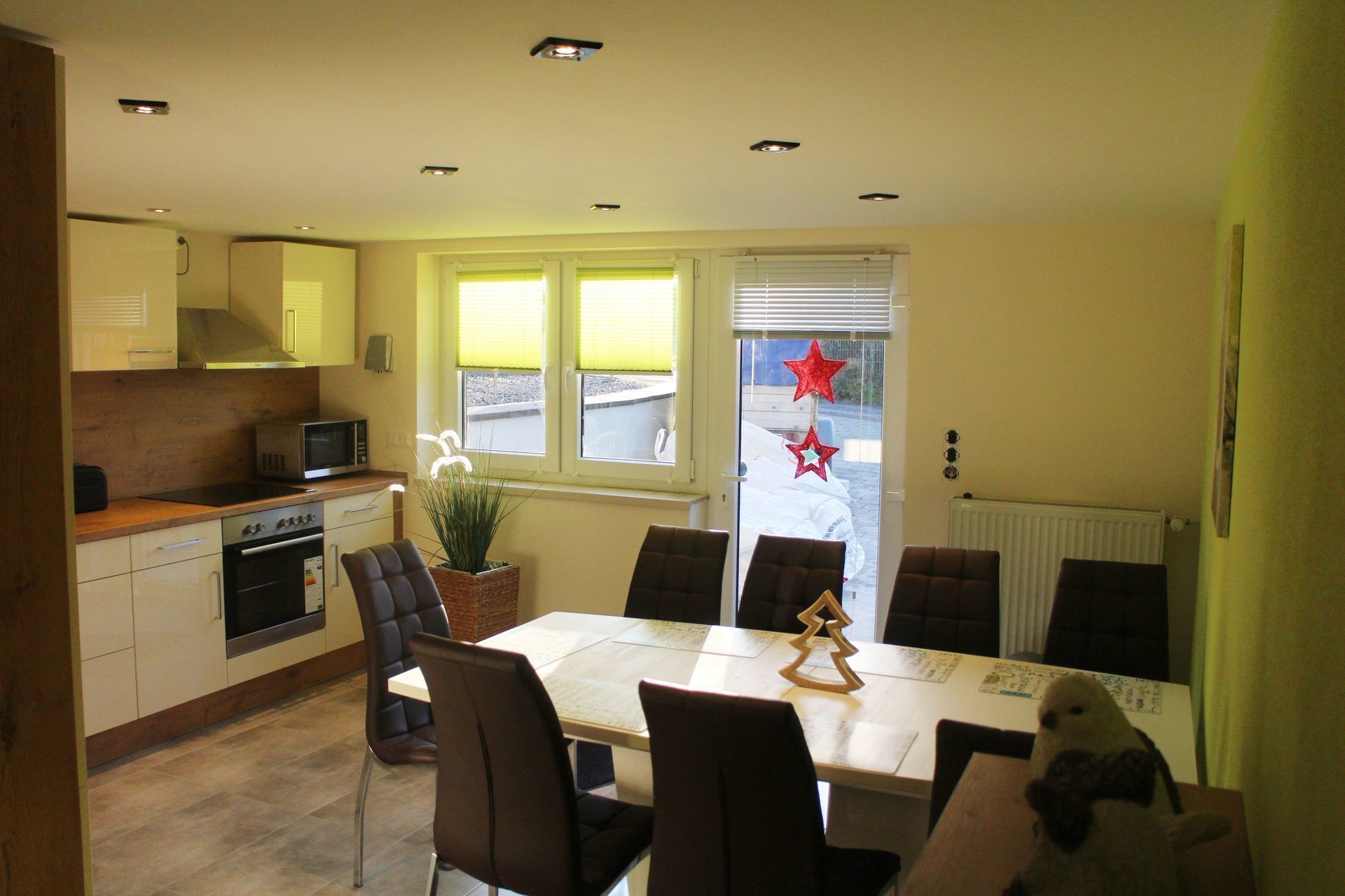 A modern kitchen with a dining area, featuring a central island, chairs, and a table.