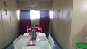 Une salle de conférence avec une longue table, des chaises, une cafetière et un lustre.