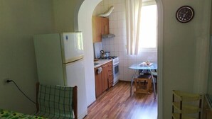 Een kleine keuken met een koelkast, fornuis en houten kastjes.