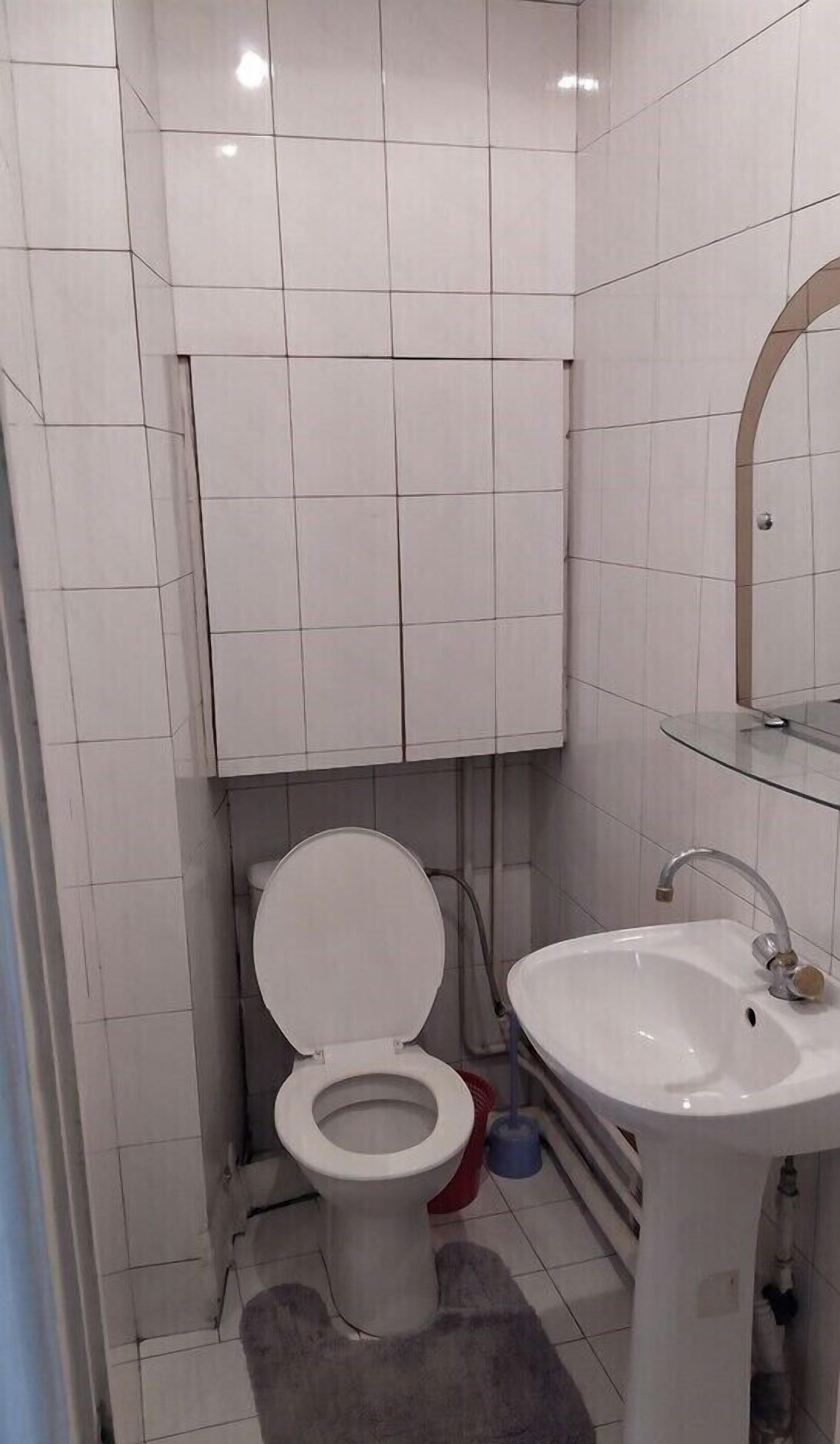A small, compact bathroom with a toilet, sink, and mirror.