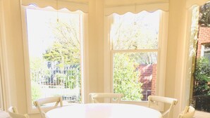 A round table with six chairs around it, positioned in a corner with large windows. - The Heart of Geelong (Geelong)