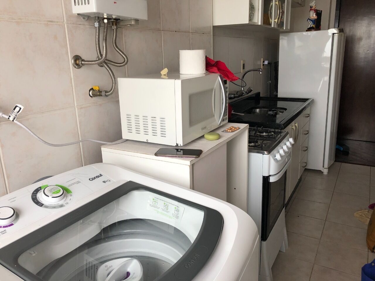 A compact kitchen with a washing machine, a microwave, a stove, and a refrigerator.