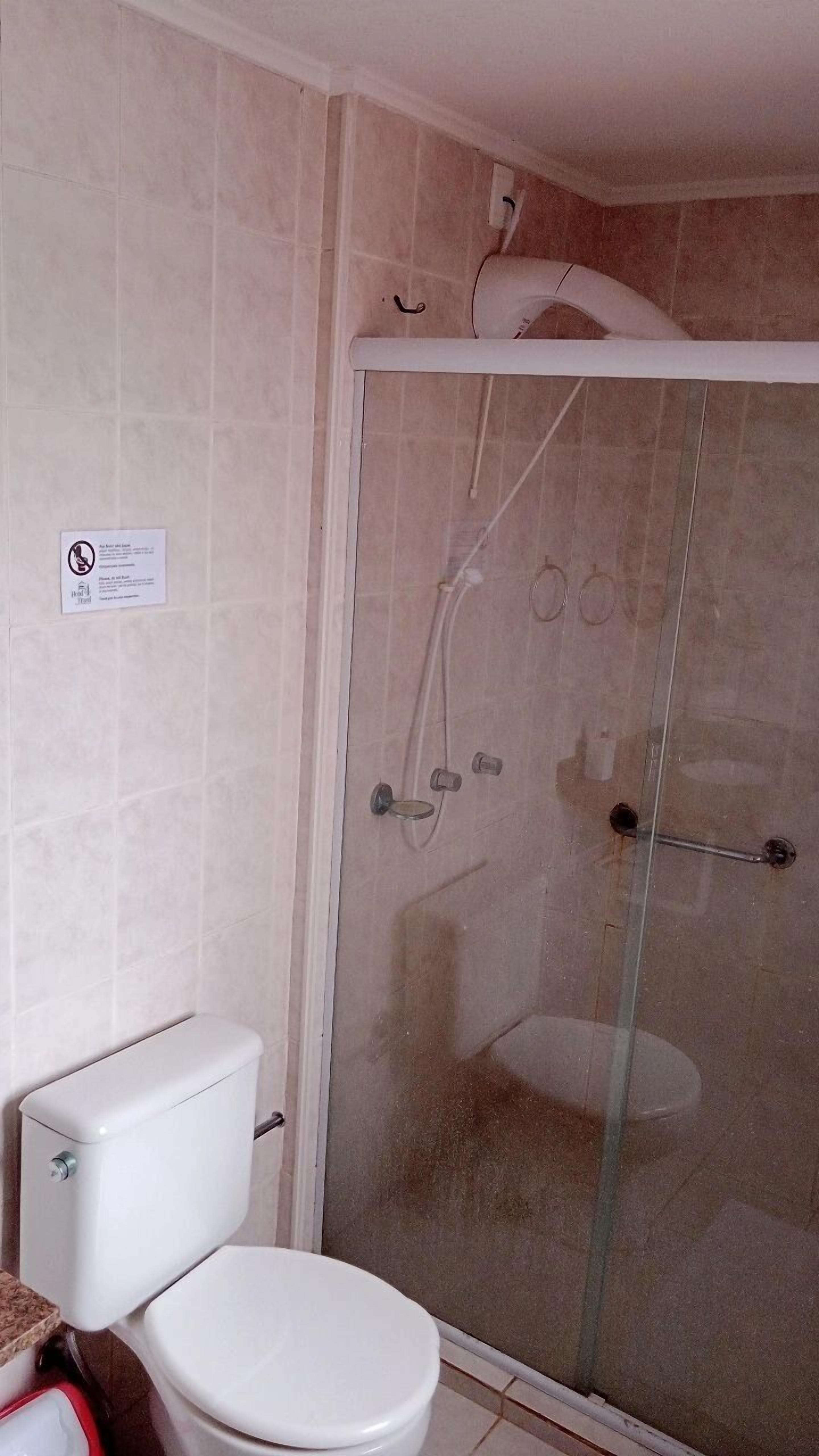 A bathroom with a toilet, a glass-enclosed shower, and a white sink.