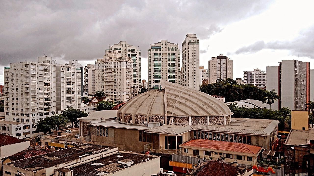 A large, historic building with a prominent dome and arched windows, surrounded by modern high-rise buildings.