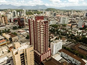 A high-rise building with multiple floors, surrounded by other buildings and palm trees.
