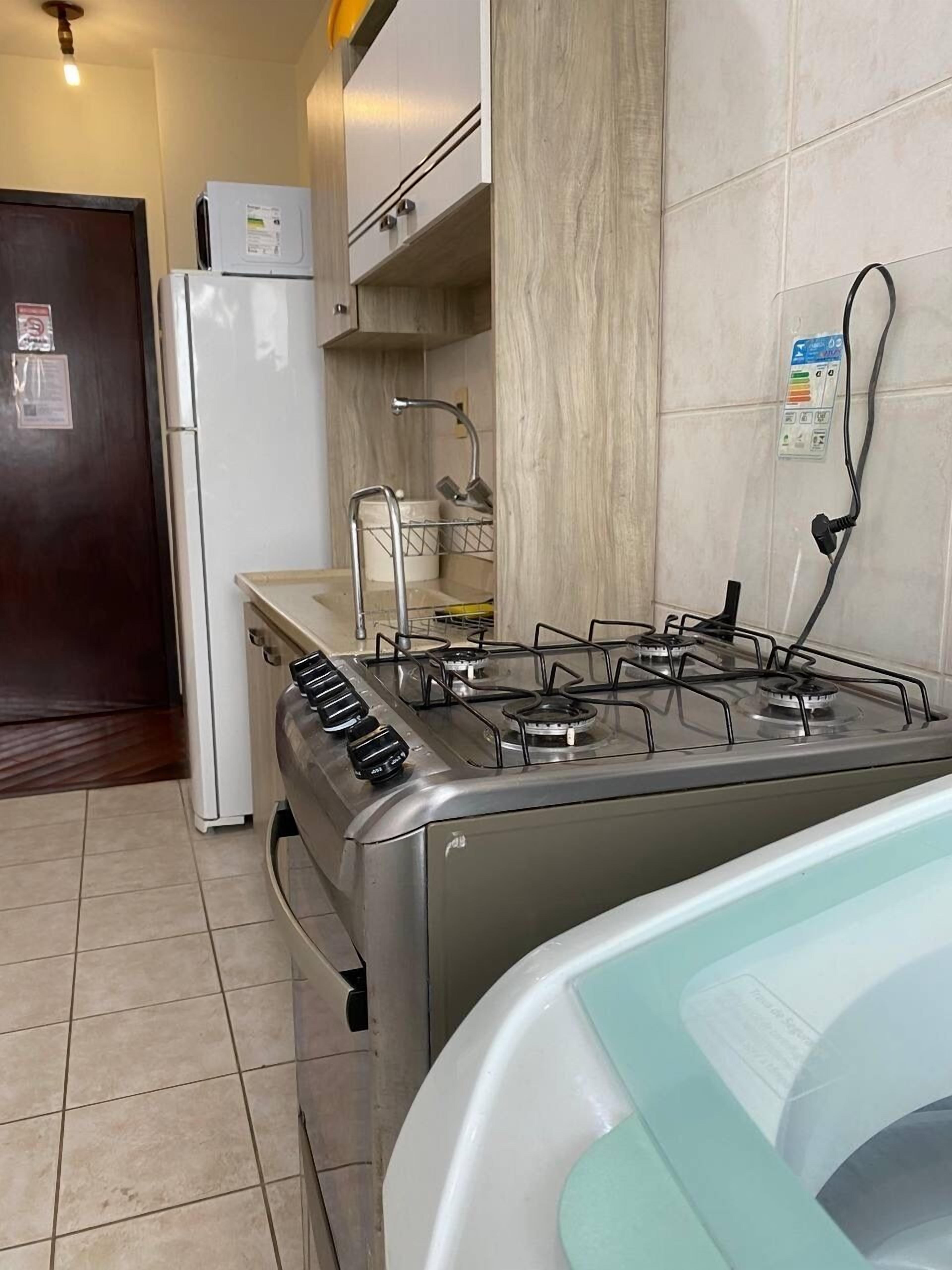 A compact kitchen with a gas stove, a refrigerator, and a sink.