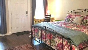 Une chambre à coucher avec un lit, un ventilateur de plafond, une porte et une fenêtre avec des rideaux.