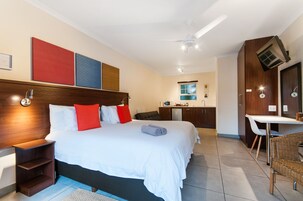 A hotel room with a large bed, a desk, and a kitchenette.