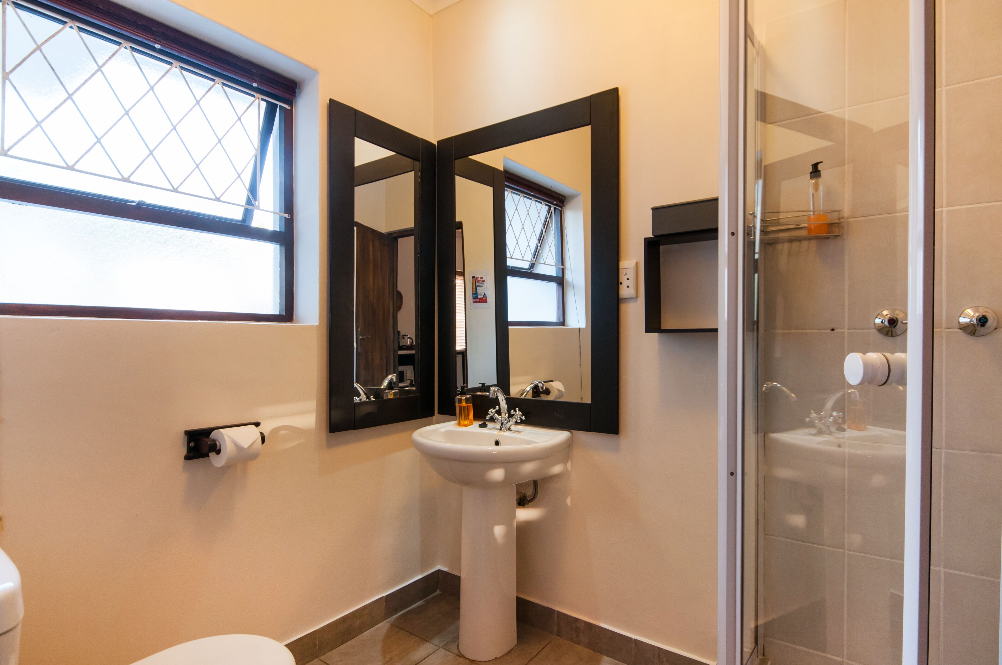 A bathroom with a toilet, a sink, a mirror, and a shower.