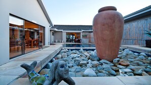 Un edificio moderno con piscina, esculturas de piedra y una maceta grande.