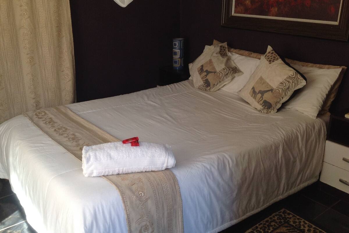 A neatly made bed with a white duvet, decorative pillows, and a folded towel on the side.