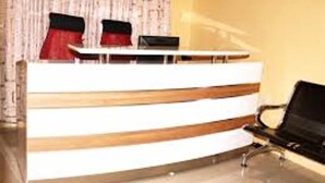 A reception desk with a modern design, a black chair, and a laptop on the desk.