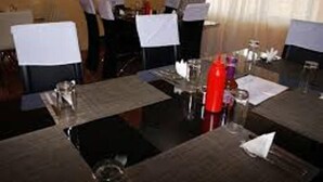 A dining area with tables set for a meal, chairs, and a window with curtains.