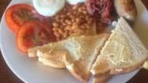 A plate with eggs, beans, tomatoes, sausages, and toast.