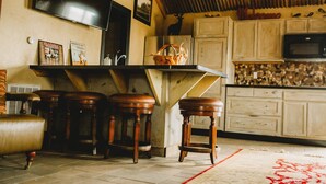 A cozy kitchen with wooden stools, a TV, and a rustic decor. - Garden Cottage at Rockin Star Ranch (Brenham)