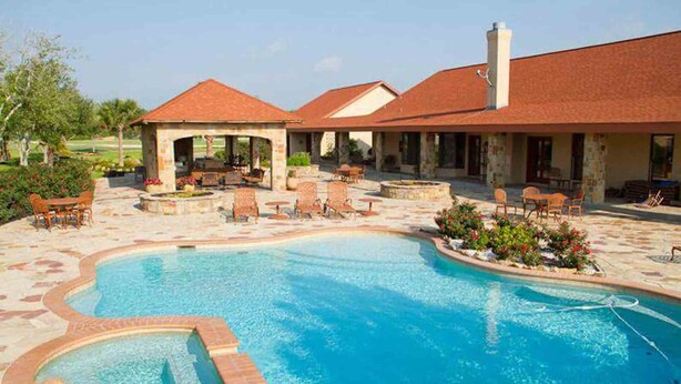 A swimming pool with a patio area, outdoor seating, and a covered section. - Garden Cottage at Rockin Star Ranch (Brenham)