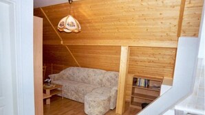 Un salon chaleureux avec un canapé, un pouf et une bibliothèque en bois.
