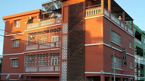 Un hôtel à plusieurs étages, doté de balcons, d’une enseigne indiquant qu’il s’agit d’un hôtel et d’une entrée bien visible.