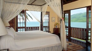 A bedroom with a large bed, a canopy, and a view of the sea through open doors. - Bluefields Bay Villas (Bluefields)