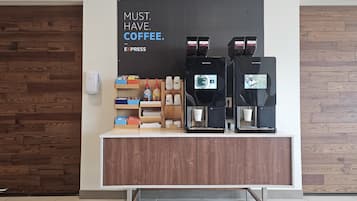 A coffee station with two espresso machines, a coffee dispenser, and a sign that reads 'MUST. HAVE. COFFEE.'