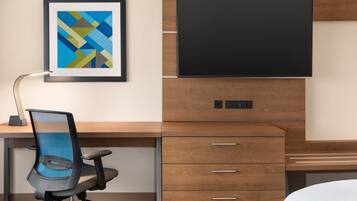 Habitació d'hotel moderna amb escriptori de fusta, televisió de pantalla plana, quadre abstracte emmarcat i cadira d'oficina de malla blava.