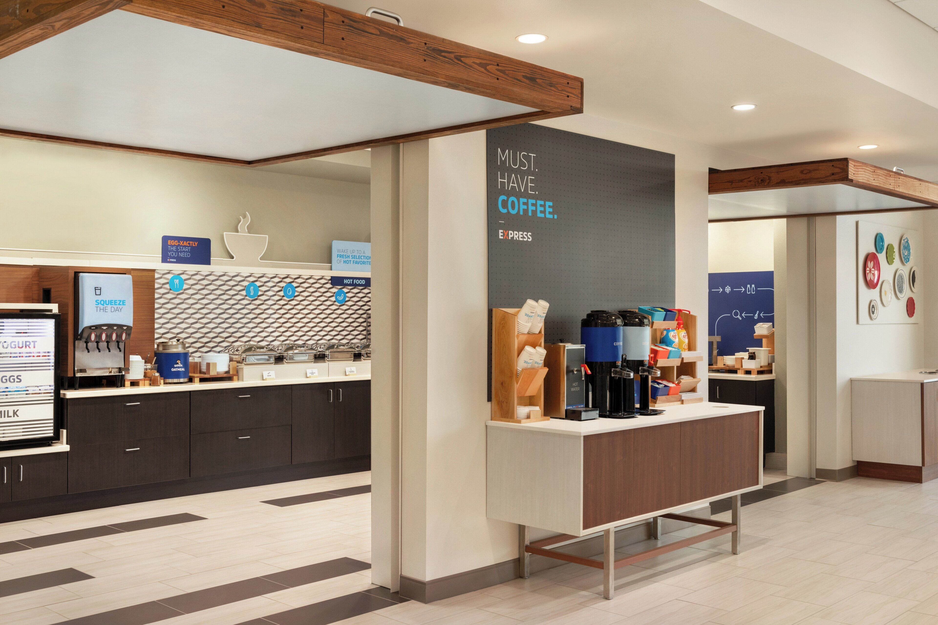 Interior moderno de una cafetería con mostrador, máquinas de café y un letrero que dice 'MUST HAVE COFFEE'.