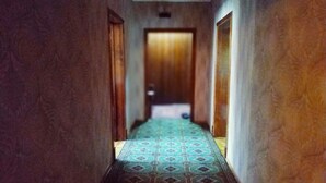A narrow hallway with patterned carpet leading to a wooden door at the end. - Welcome Home 7 (Tashkent)