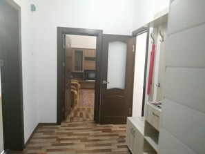 A hallway with a wooden floor leading to a room with a television, a sofa, and a patterned rug. - Welcome Home 19 (Tashkent)