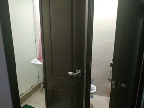 Une salle de bain avec un lavabo blanc, des toilettes et une porte sombre.