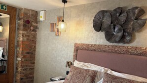 A neatly made bed with two pillows, a headboard, and a decorative wall piece. - Rylands Farmhouse (Wilmslow)