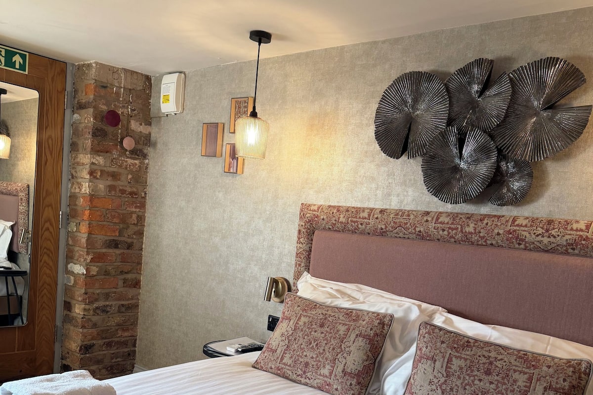 Un lit bien fait, avec deux oreillers, une tête de lit et un élément décoratif mural.