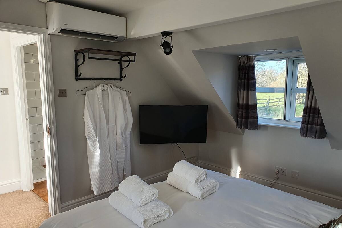 Une chambre avec un lit, un téléviseur à écran plat, un porte-serviettes et une fenêtre avec des rideaux.