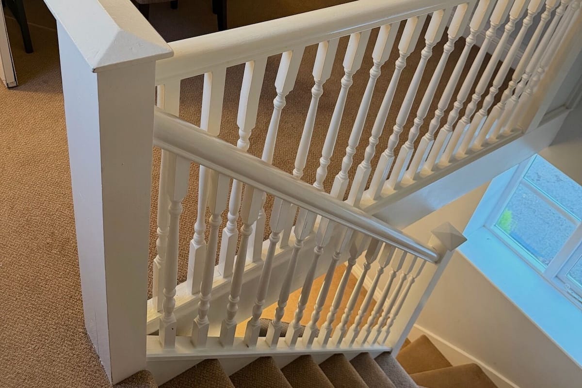 Un escalier avec des balustrades blanches et un revêtement de sol en moquette.