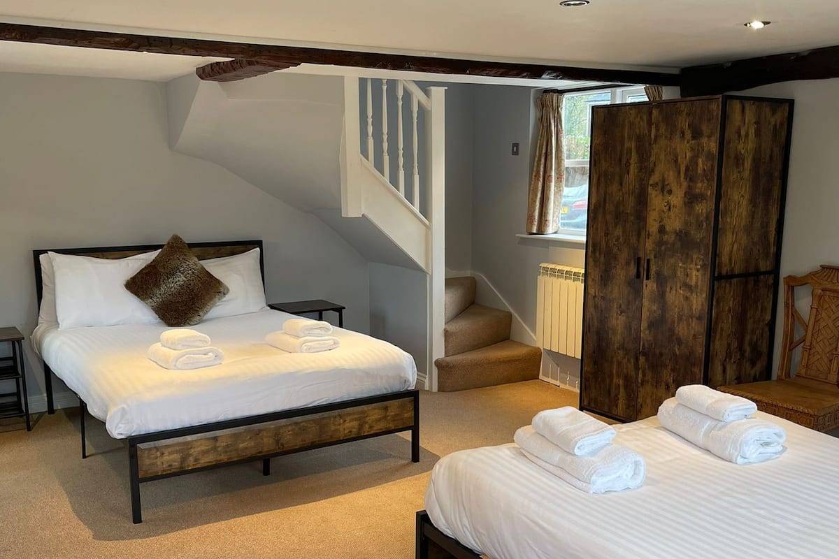 Une chambre avec deux lits, un escalier et une armoire.