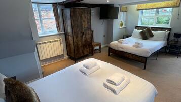 A bedroom with a large bed, a wooden wardrobe, a television, and a window with curtains.