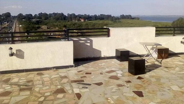 A rooftop terrace with a stone floor, a table, and chairs.