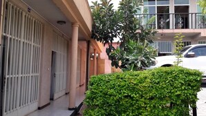 A building with a covered entrance, a car parked in front, and a well-maintained hedge.
