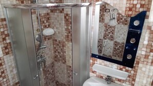 A bathroom with a glass-enclosed shower, a white sink, and a tiled backsplash.