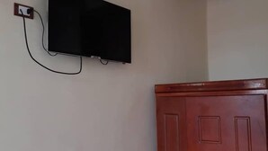 A room with a mounted television on the wall and a wooden wardrobe.