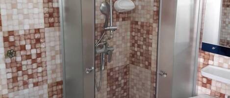 A bathroom with a shower enclosure, a toilet, and a sink.