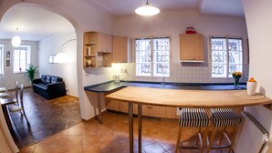 A modern kitchen with a central island, wooden cabinets, and a dining area with a black leather couch. - St. Nicholas Church view apartment (Prague)