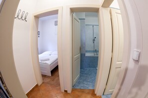 Un couloir étroit menant à une chambre et à un espace douche.