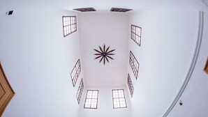 A room with a high ceiling, multiple windows, and a star-shaped light fixture. - St. Nicholas Church view apartment (Prague)