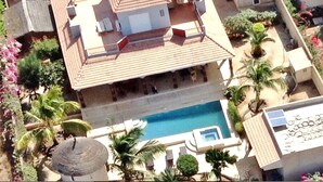A large house with a swimming pool, surrounded by palm trees and other greenery. - Villa Elodie (La Somone)
