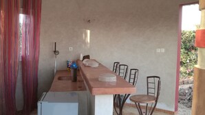 A compact kitchen with a central island, a refrigerator, and a dining area with two chairs. - Villa Elodie (La Somone)